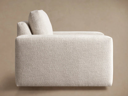 Kipton Wide Arm Swivel Chair in light beige textured fabric, seen from a three-quarter rear view, showing wide block arms.