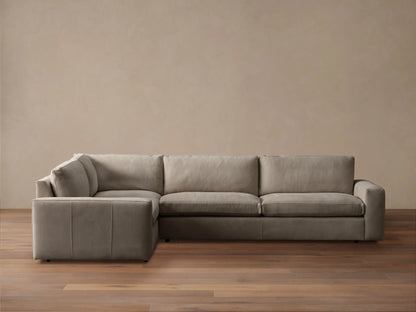 Kipton L-shaped, two-piece, wide-arm sectional sofa in light taupe nubuck leather with plush cushions, against a neutral wall.