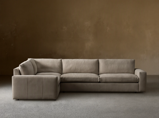 Kipton L-shaped, two-piece, wide-arm sectional sofa in light taupe nubuck leather with plush cushions, against a neutral wall.
