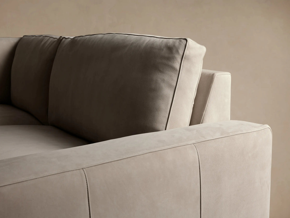 L-shaped Kipton Wide Arm Two-Piece Sectional sofa in light greige nubuck leather, on a wooden floor against a neutral wall.