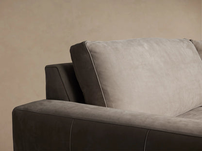 Kipton Wide Arm Nubuck Leather Sofa, light taupe, with wide boxy arms, two back & seat cushions, on a wooden floor.