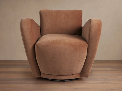 Front-right view of a plush, curved, rust-colored velvet Amelia Swivel Chair on a black swivel base, set on a wooden floor.