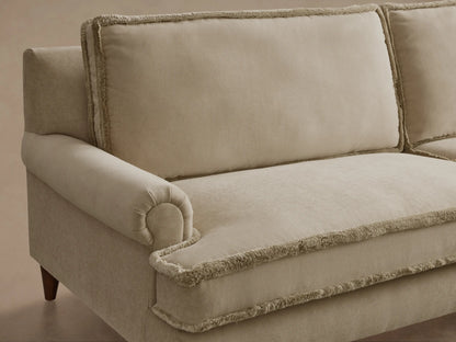 Rear view of the beige McKinley Sofa, featuring fringed back cushions and dark wood tapered legs.