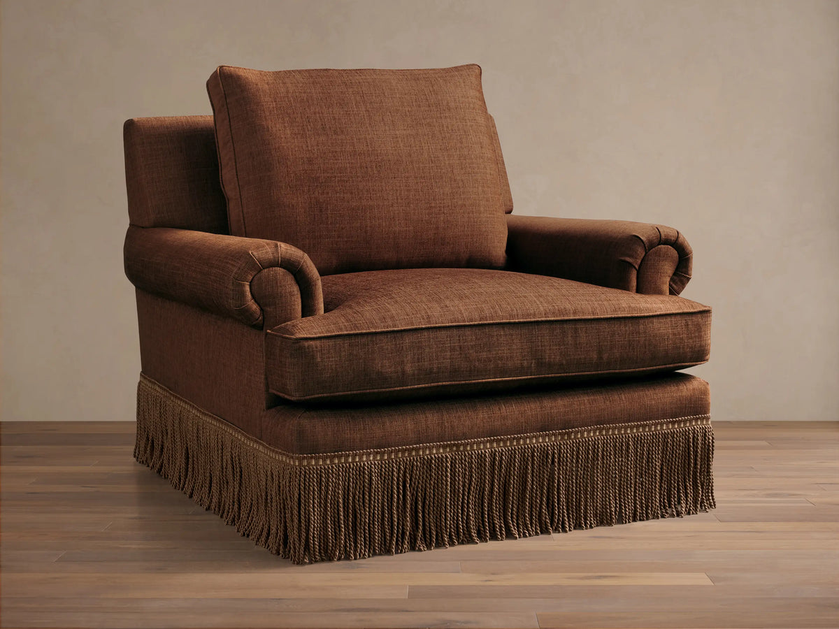 Front view of a brown McKinley Chair with Fringe, featuring rolled arms and a decorative fringed skirt.
