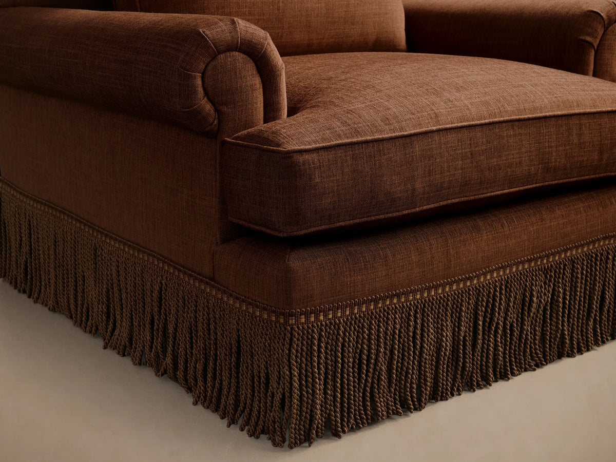 Front view of the rust McKinley Chair with Fringe, featuring rolled arms, a loose back cushion, and decorative rope fringe.