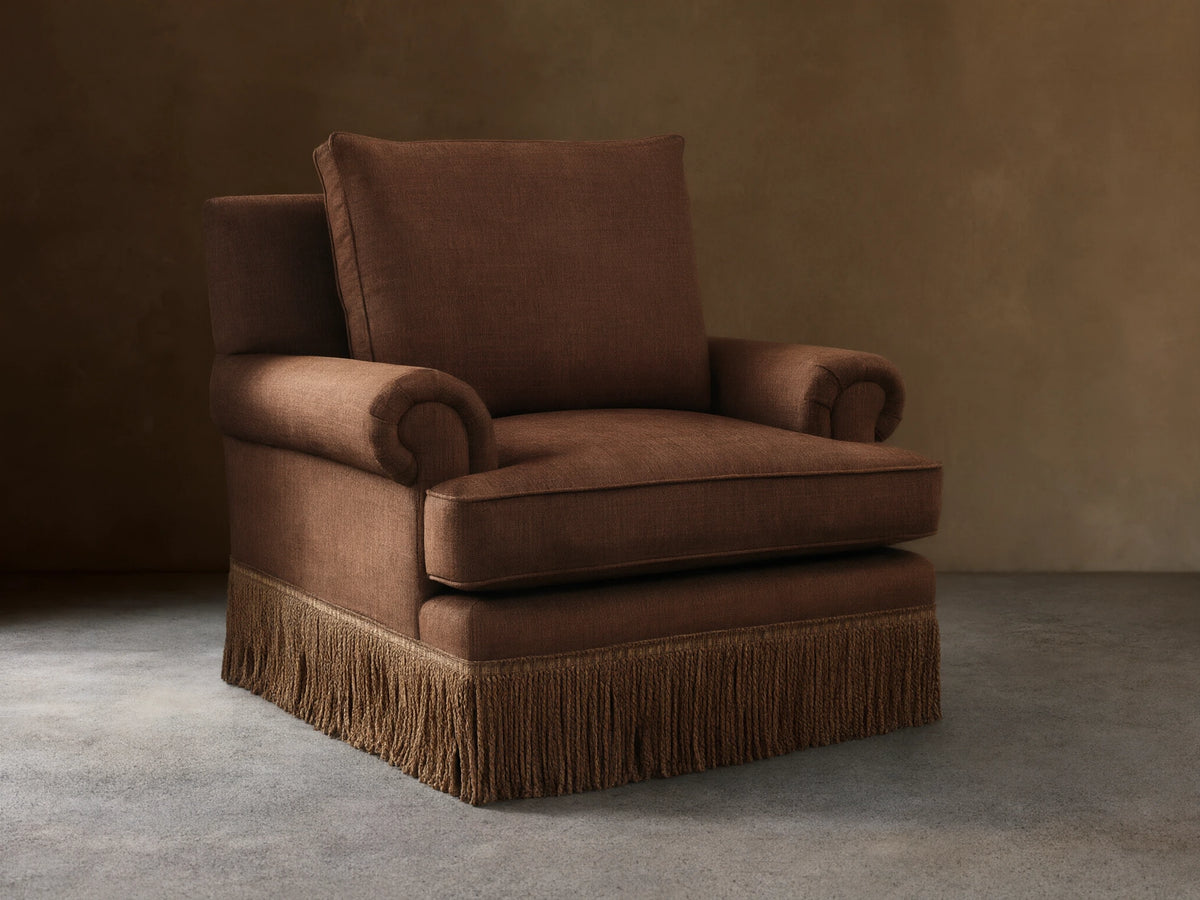 Front view of a brown McKinley Chair with Fringe, featuring rolled arms and a decorative fringed skirt.