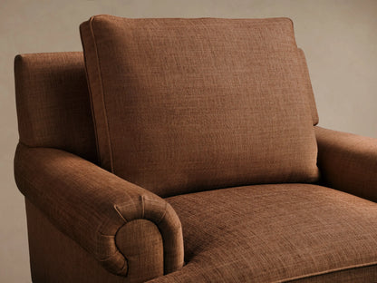 Close-up of the textured brown McKinley Chair with Fringe, showing a rolled armrest, seat cushion, and braided fringe skirt.