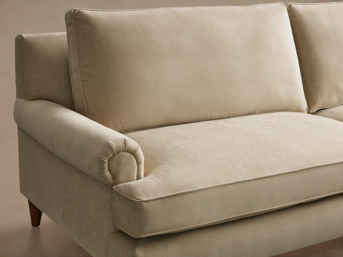 Angled front view of a light beige McKinley Sofa, featuring rolled arms, two seat cushions with piped edges, and tapered wooden legs.