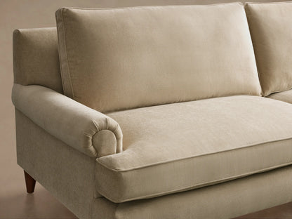 Angled front view of a light beige McKinley Sofa, featuring rolled arms, two seat cushions with piped edges, and tapered wooden legs.