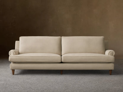 Front view of the oatmeal McKinley Sofa, featuring two large seat cushions, two plush back cushions, rolled arms, and dark wooden legs.