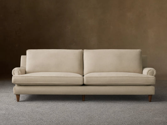 Front view of the oatmeal McKinley Sofa, featuring two large seat cushions, two plush back cushions, rolled arms, and dark wooden legs.