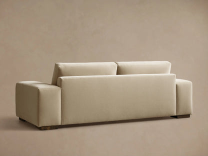 Rear view of the cream Madson Sofa with square arms and dark wooden feet, angled left.