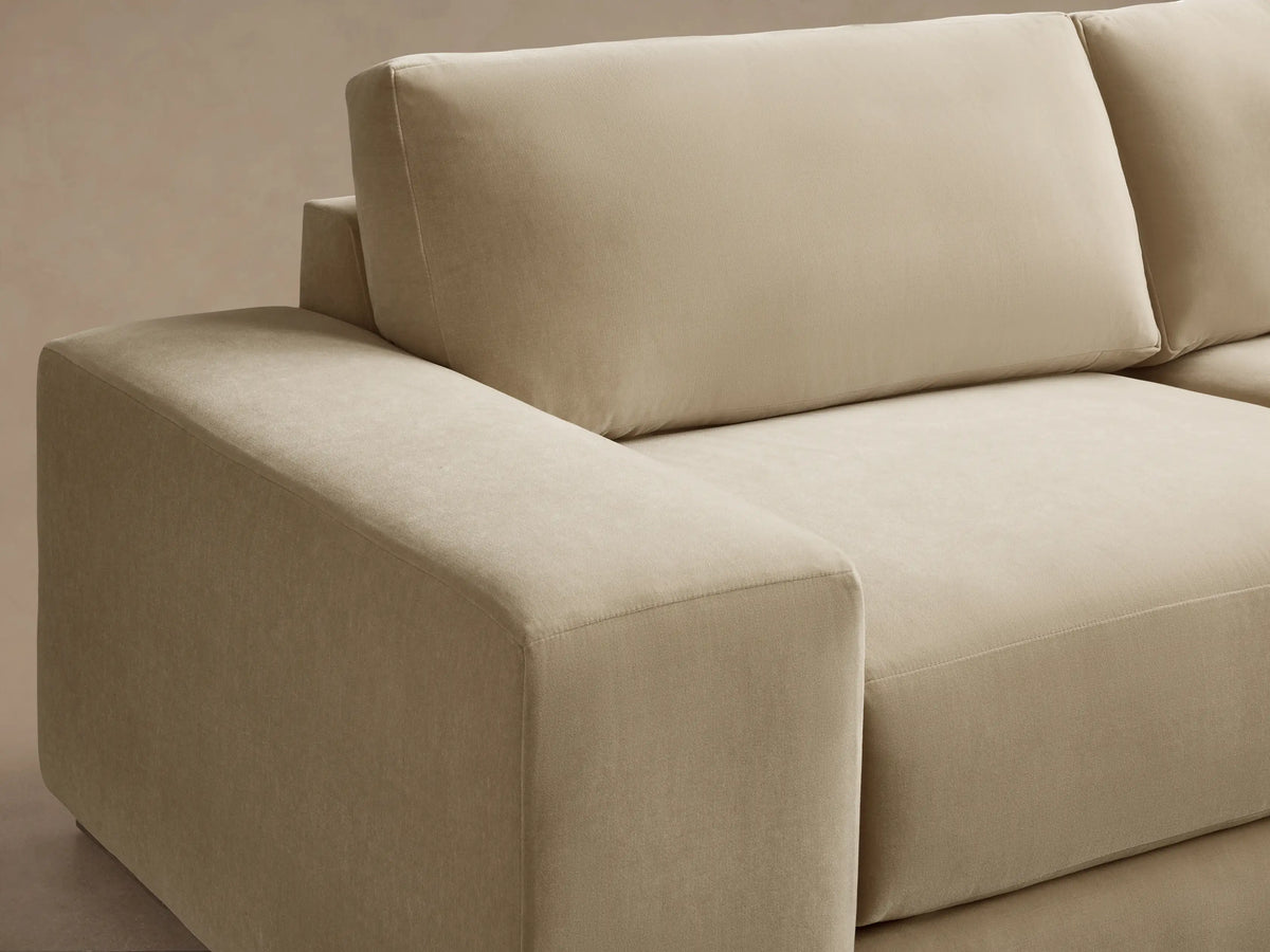 Front view of a cream Madson Sofa with two seat cushions, two back cushions, blocky armrests, and a low dark wooden base.