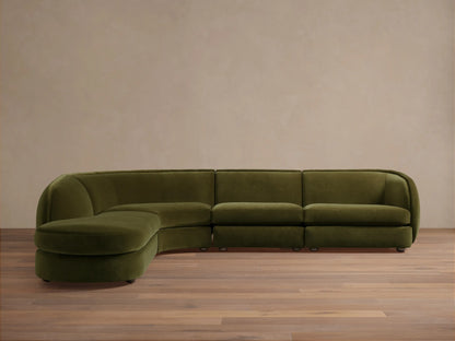 Olive green Milana Four-Piece Bumper Sectional on wooden floor, featuring armless chair, corner wedge, and arm chairs in a crescent shape.