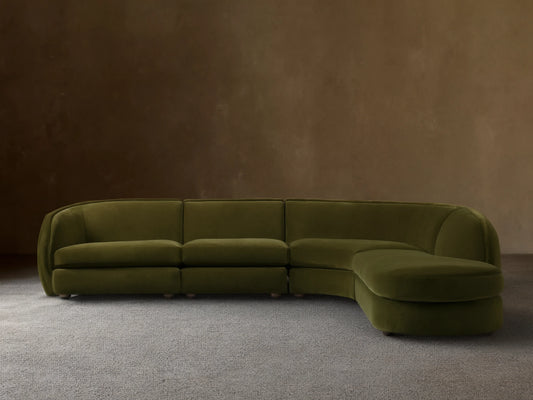 Olive green Milana Four-Piece Bumper Sectional on wooden floor, featuring armless chair, corner wedge, and arm chairs in a crescent shape.
