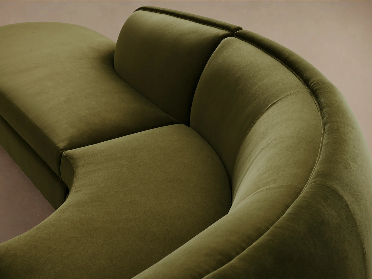 Milana Four-Piece Bumper Sectional in olive green fabric, showcasing curved design, set on wooden floor against beige wall.