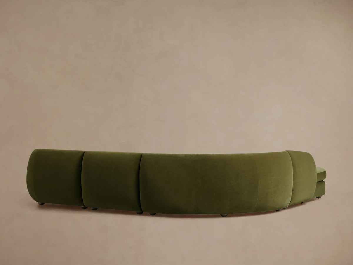 Milana sectional in olive-green fabric, showcasing a curved, plush design with deep cushioning against a neutral background.