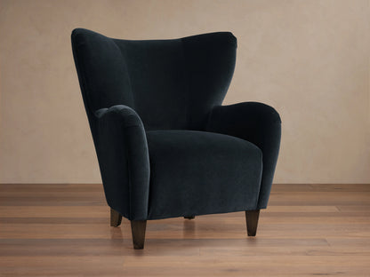 Front 3/4 view of the dark navy Myra Chair, a high-backed wingback chair with rounded arms and dark wood legs.