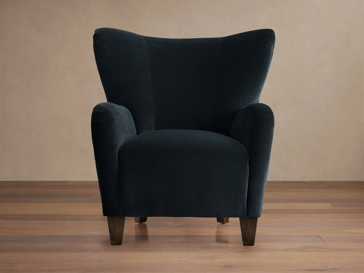 Front 3/4 view of the dark navy Myra Chair, a high-backed wingback chair with rounded arms and dark wood legs.