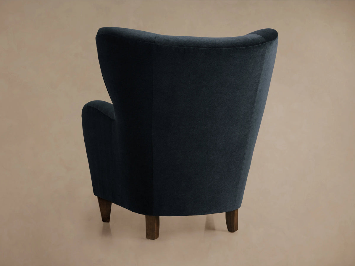 Close-up of the deep navy blue upholstered Myra Chair, showing the curved armrest, seat, and backrest.