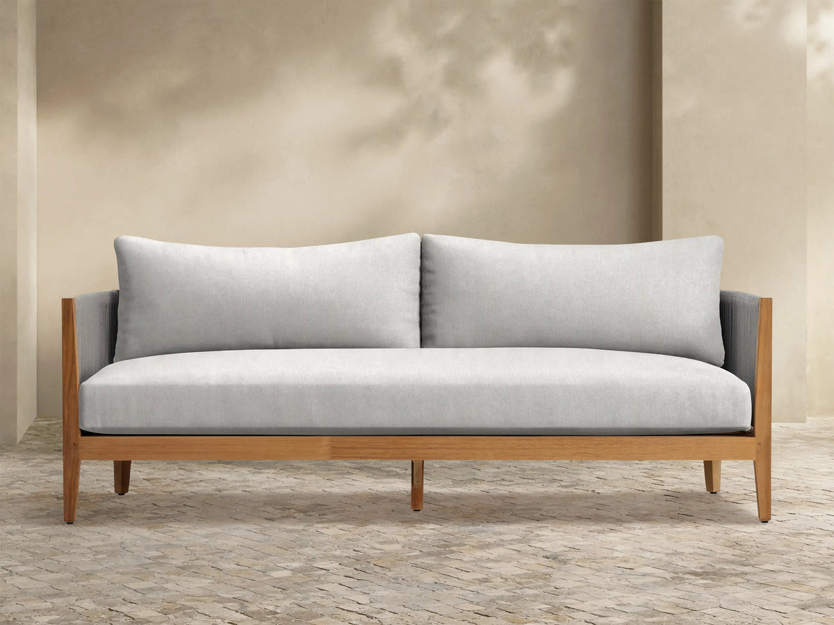 Front view of the Newport Outdoor Sofa with light grey cushions, natural teak frame, and grey woven rope armrests.