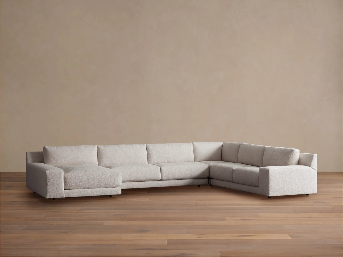 Light beige Novoli Four-Piece Chaise Sectional with left chaise and ribbed right arm, on a wood floor against a plain wall.