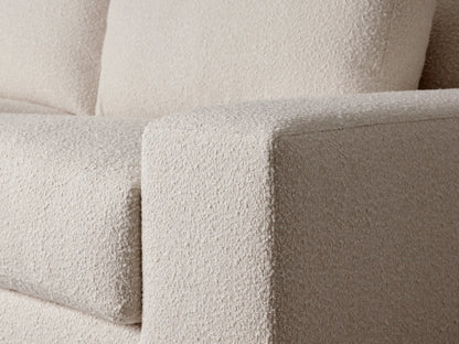 Novoli Sofa, a light cream textured boucle two-seater sofa with two large seat cushions and two back cushions, on a wood floor.