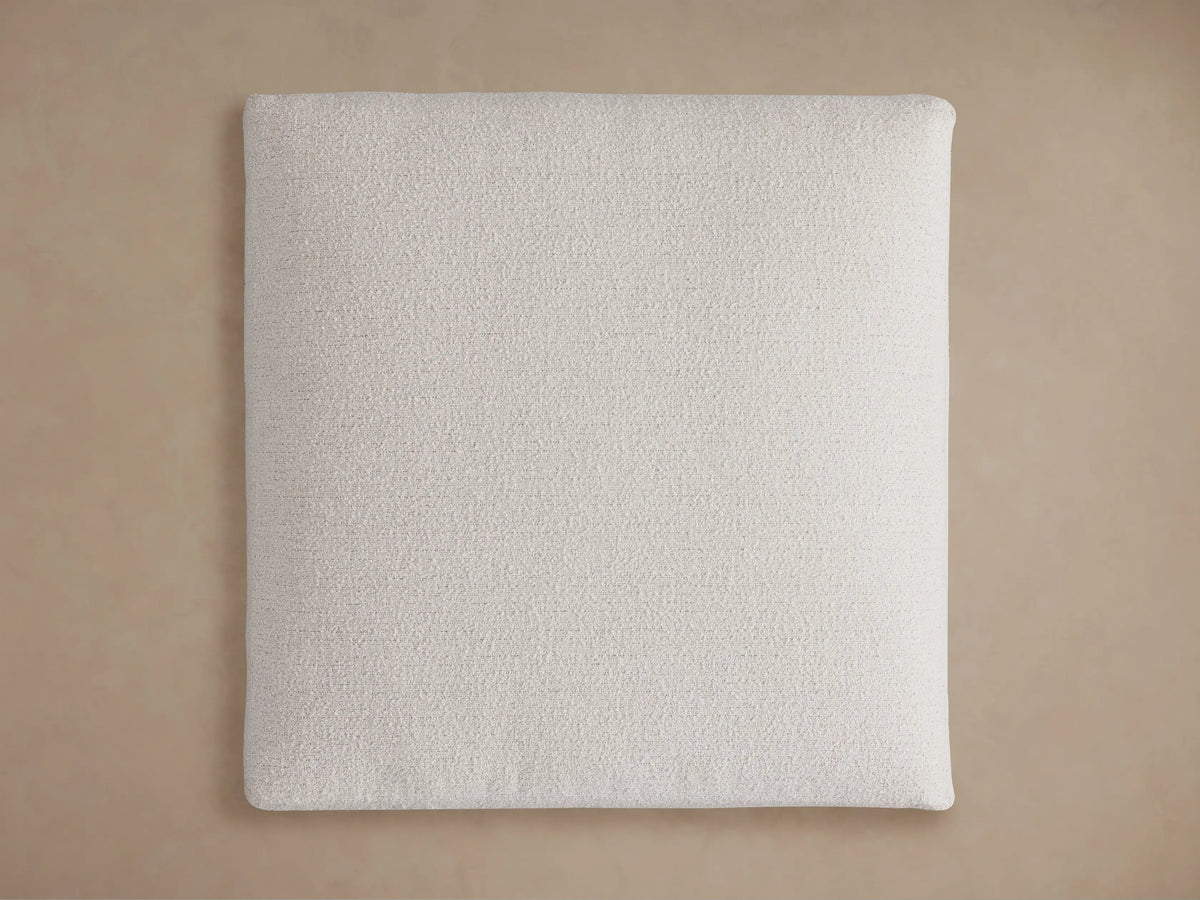 Light beige textured Novoli Ottoman, showing distinct cushions in a bouclv©-like fabric on a warm background.