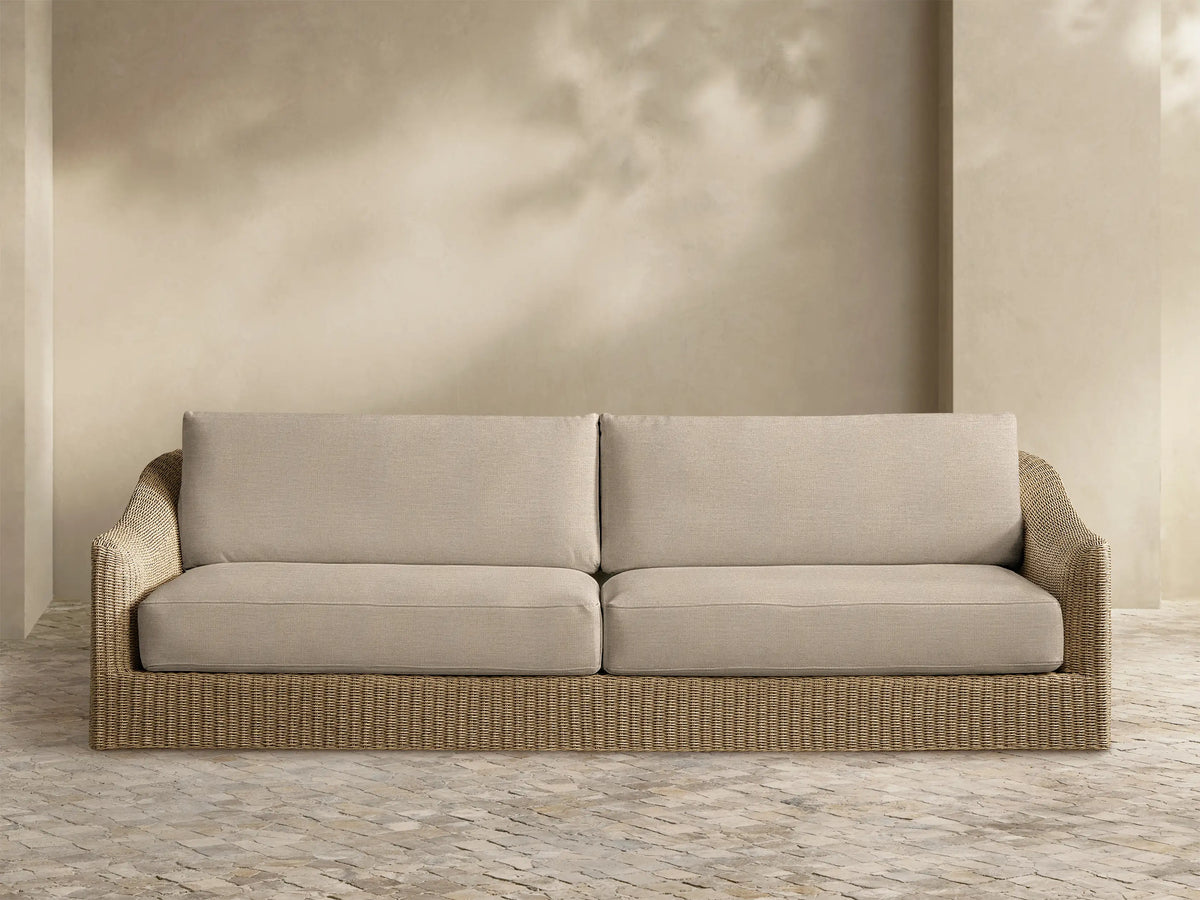 Front view of the Ancona Outdoor Sofa, featuring a light brown handwoven wicker frame and two beige seat and back cushions.