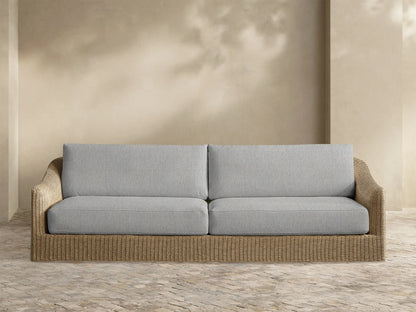 Front view of the Ancona Outdoor Sofa with natural brown handwoven all-weather wicker and light grey cushions.