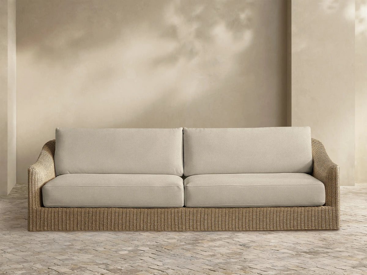 Front view of the natural woven Ancona Outdoor Sofa with light beige seat and back cushions.