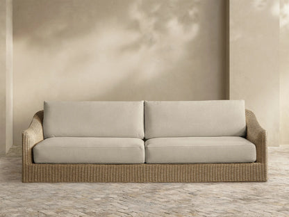 Front view of the natural woven Ancona Outdoor Sofa with light beige seat and back cushions.