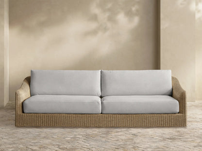 Front view of the Ancona Outdoor Sofa, featuring a natural woven wicker base and light gray seat and back cushions.