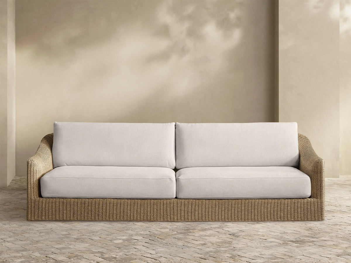 Front view of Ancona Outdoor Sofa with light beige cushions and a natural brown woven wicker base.