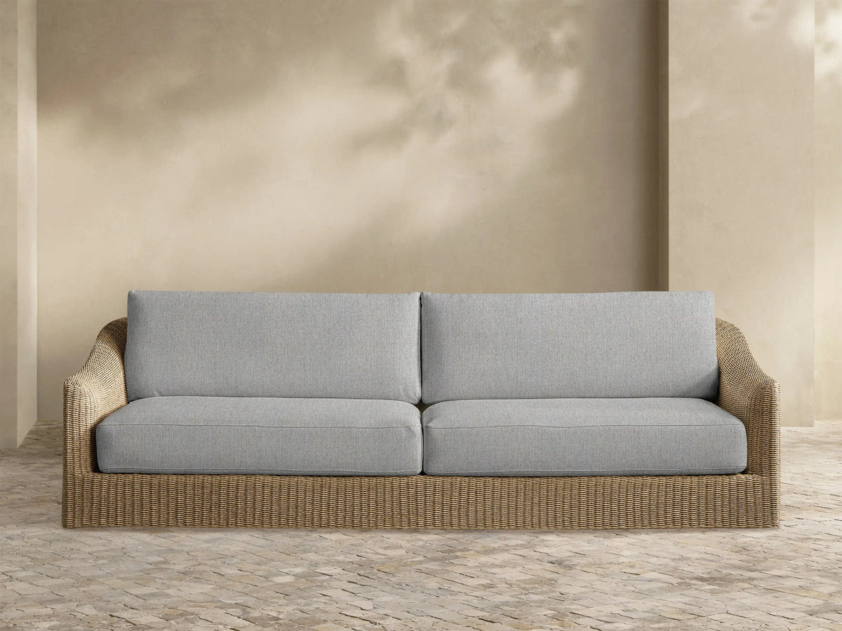 Front view of the Ancona Outdoor Sofa, featuring light gray cushions and a handwoven natural-toned wicker frame.