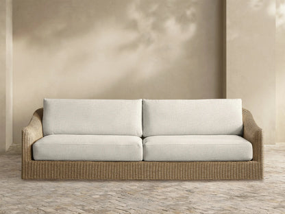 Front view of the Ancona Outdoor Sofa with a handwoven natural all-weather wicker frame and two cream fabric cushions.
