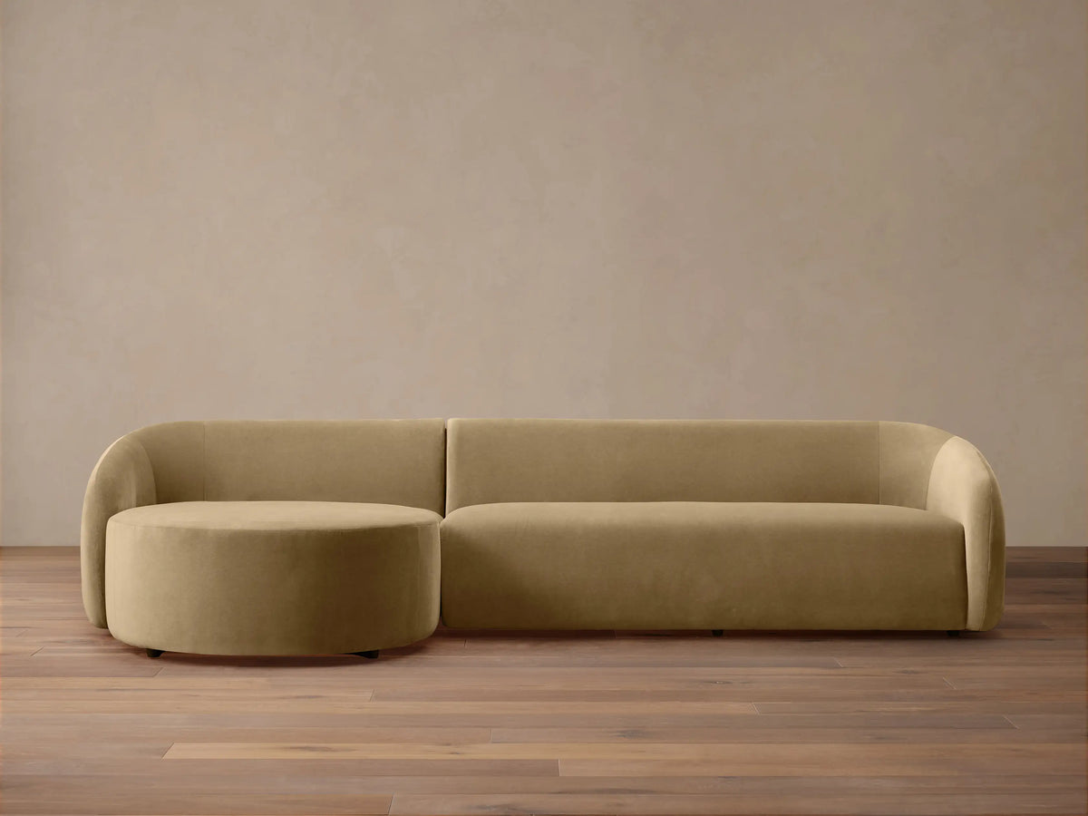 Modern, rounded light brown velvet Fresno Two-Piece Chaise Sectional with attached round chaise, on wood floor.