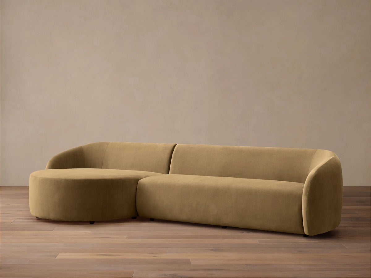 Modern, rounded light brown velvet Fresno Two-Piece Chaise Sectional with attached round chaise, on wood floor.