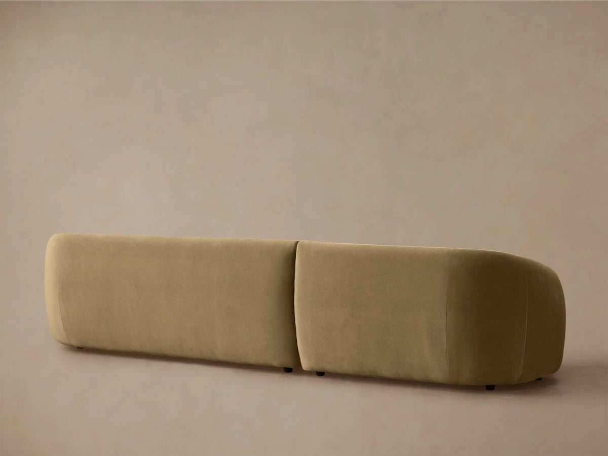 Close-up, angled view of the curved back and arm of a plush, muted tan Fresno Two-Piece Chaise Sectional.