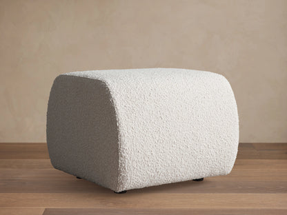 Square Fresno Ottoman featuring a beige, brown, and gray woven checkered pattern, positioned on a light rug.