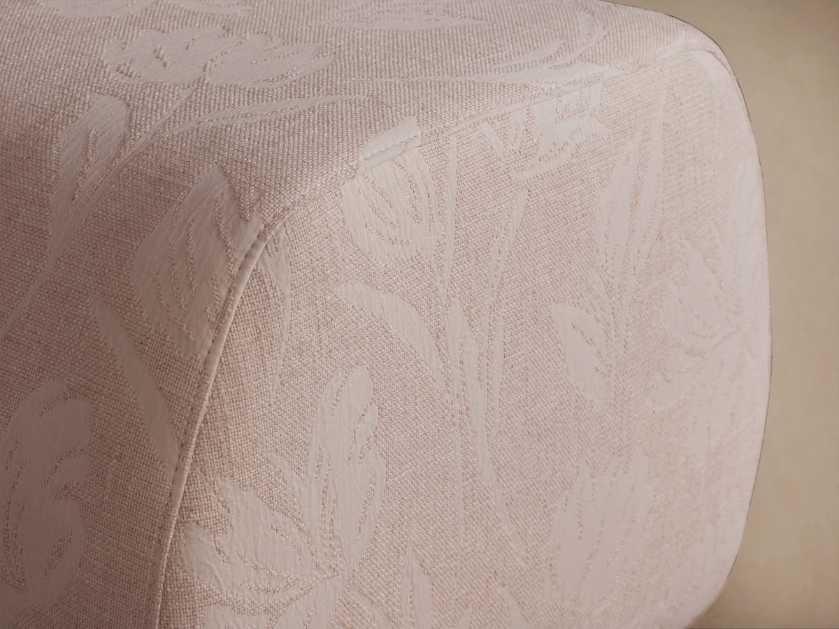 Fresno Ottoman: Light beige upholstered with subtle woven floral pattern, rounded edges, viewed at a slight angle on a neutral background.