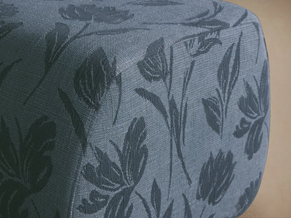 Fresno Ottoman: Rounded rectangular ottoman in light blue fabric with darker blue floral pattern, sitting on a wooden floor.