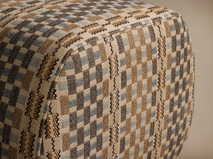 Fresno Ottoman: a rounded rectangular ottoman upholstered in a brown, beige, and blue geometric checkered fabric on a wooden floor.