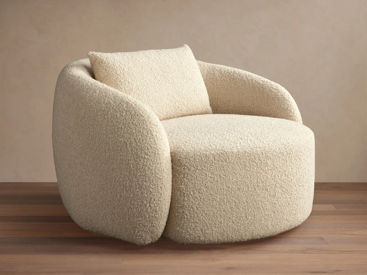 Fresno Oversized Swivel Chair in a creamy beige textured fabric, features a rounded back and plush seat with a matching pillow, set on wood floor.