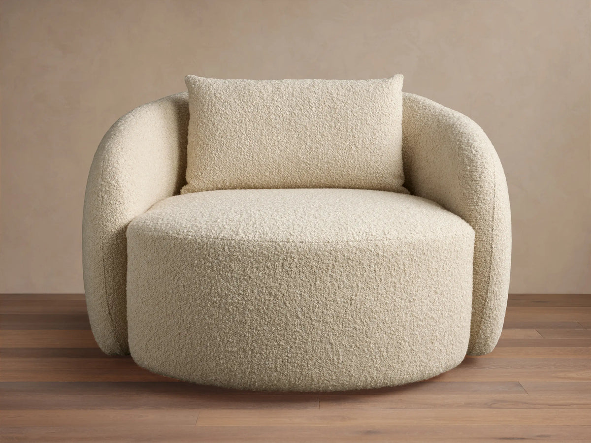 Fresno Oversized Swivel Chair in a creamy beige textured fabric, features a rounded back and plush seat with a matching pillow, set on wood floor.