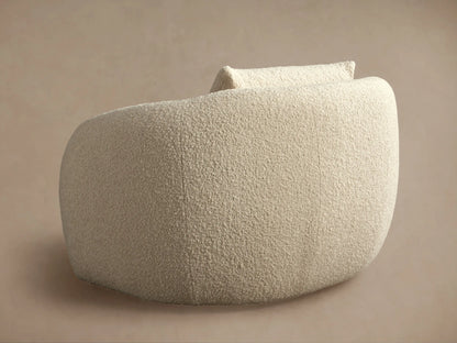 Fresno Oversized Swivel Chair in cream fabric, side view showing rounded back and seat. Soft texture, on a beige background.