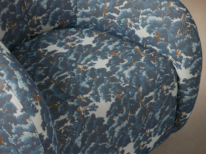Fresno Swivel Chair, rounded, upholstered in blue and white Oaks Pacific tree pattern fabric, front view on wood floor.