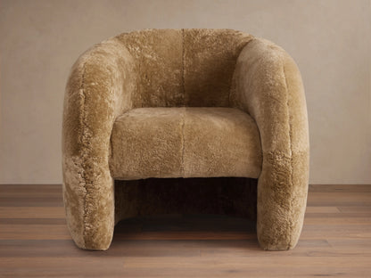 Fresno Shearling Floating Seat Chair in light brown shearling fabric. Features curved backrest and armrests with wooden floor.