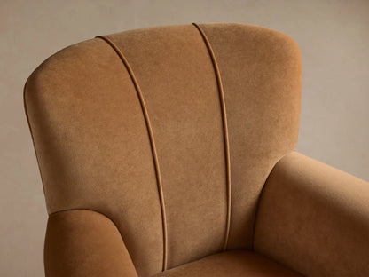 Prato Chair, front view. Upholstered in Banks Camel velvet, with rounded arms, high back, two vertical back seams. On wood floor.