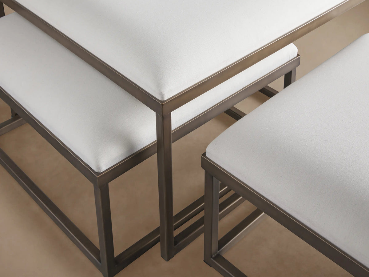 Palmer Upholstered Nesting Ottomans: Three white-cushioned ottomans with dark metal bases on a wood floor against a beige wall.